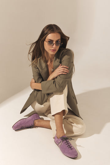 Women's olive blazer with white cropped trousers and purple suede loafers in a modern designer fashion look.